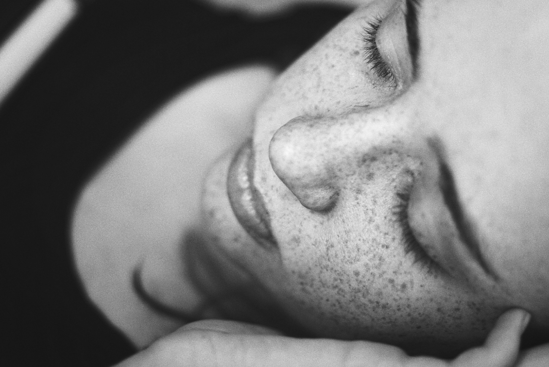 Black and white close-up of hands performing a restorative facial treatment